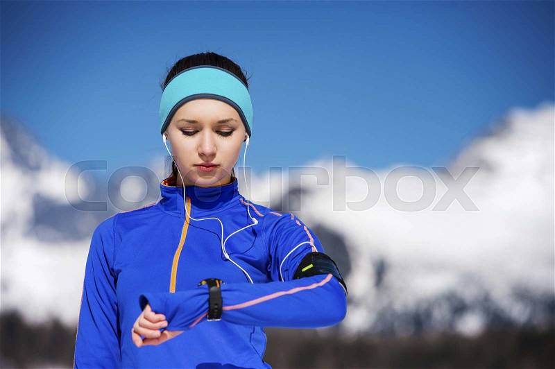 Young sportswoman jogging outside in sunny winter mountains, stock photo