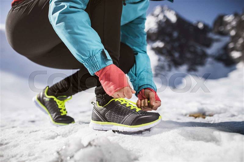 Unrecognizable woman jogging outside in sunny winter mountains, stock photo