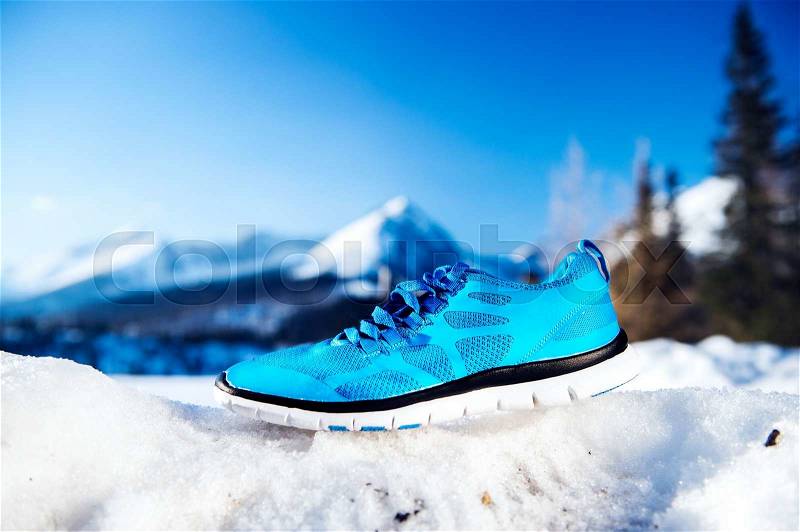 Blue running shoes laid outside on snow, stock photo