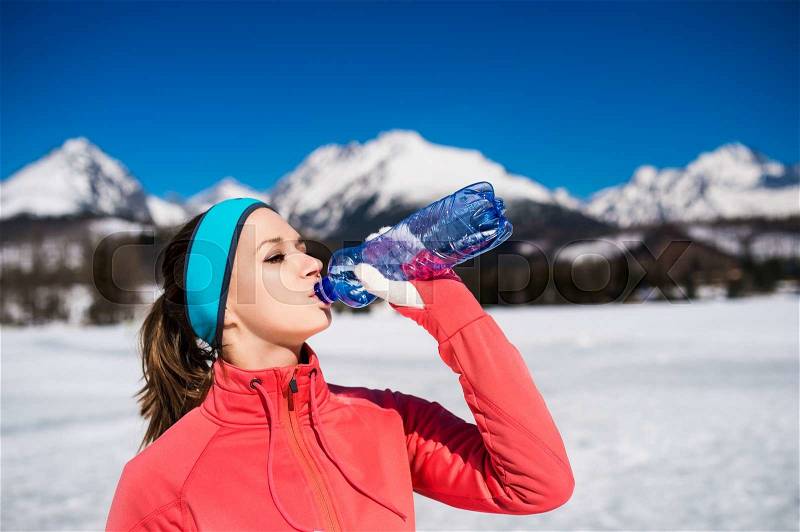 Young woman jogging outside in sunny winter mountains, stock photo
