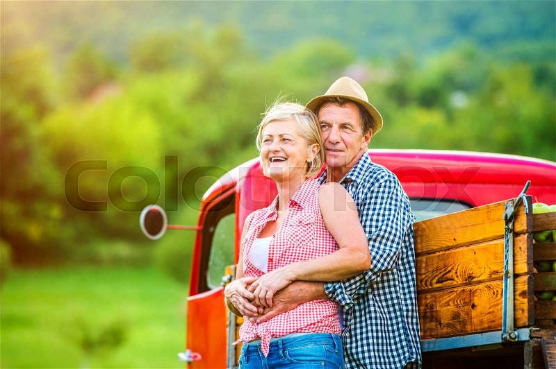 Senior couple standing next to the red truck , stock photo