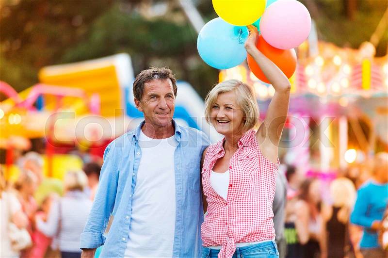 Senior couple having a good time at the fun fair, stock photo
