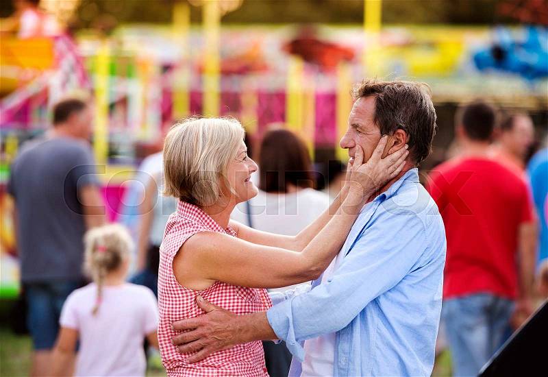 Senior couple having a good time at the fun fair, stock photo