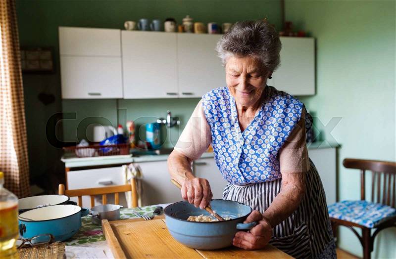 Senior woman baking pies in her home kitchen. Mixing ingredients, stock photo