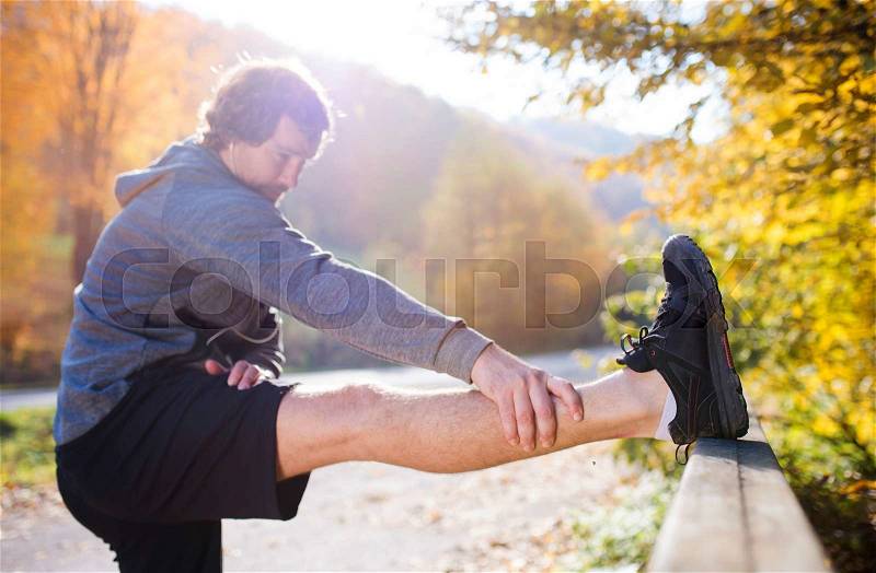 Young runner warming up and stretching on a bridge, stock photo