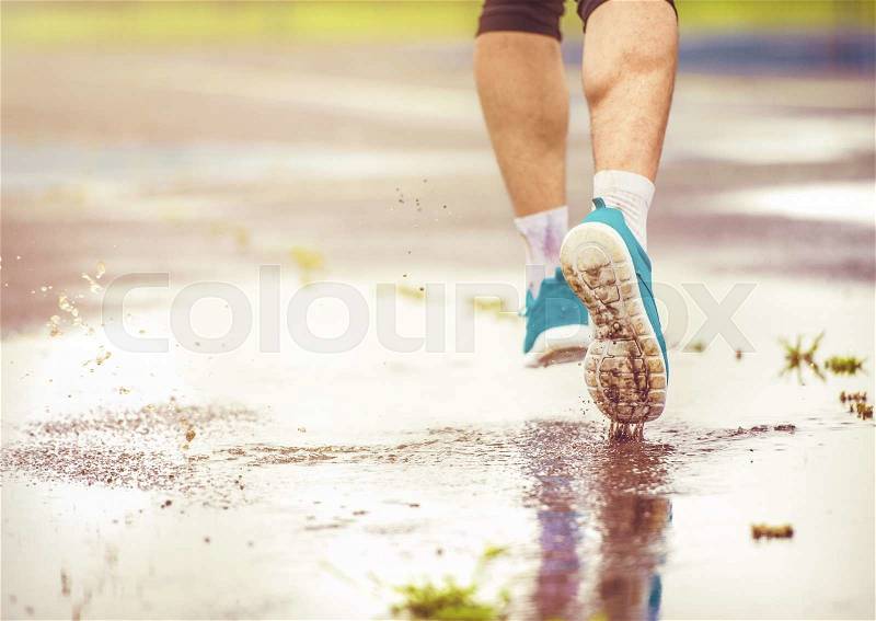 Young man jogging on asphalt in rainy weather, stock photo