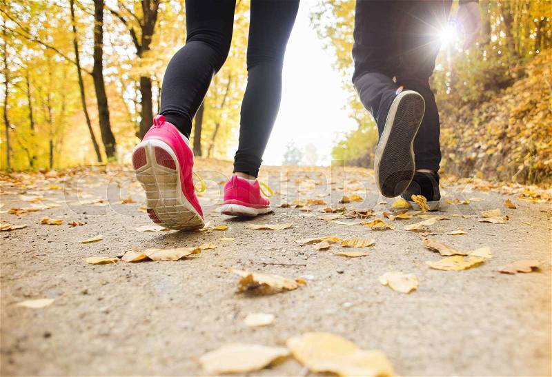 Young running couple jogging in autumn nature, stock photo