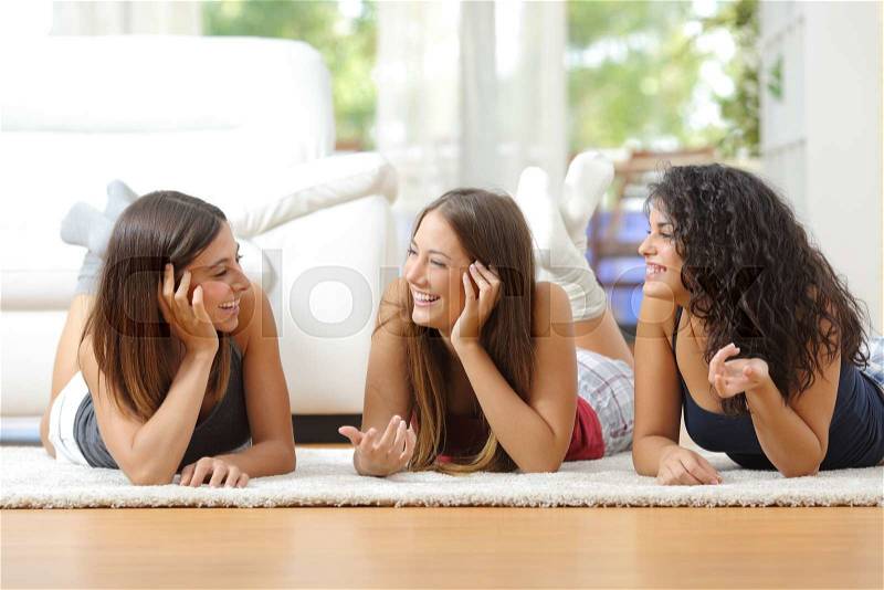 Group of happy teen friends talking lying on the floor at home, stock photo
