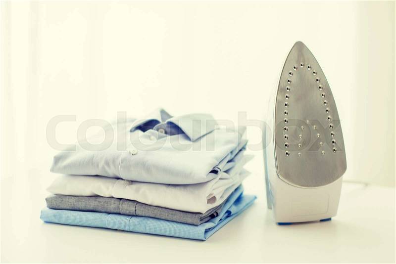 Ironing, clothes, housework and objects concept - close up of iron and clothes on table at home, stock photo