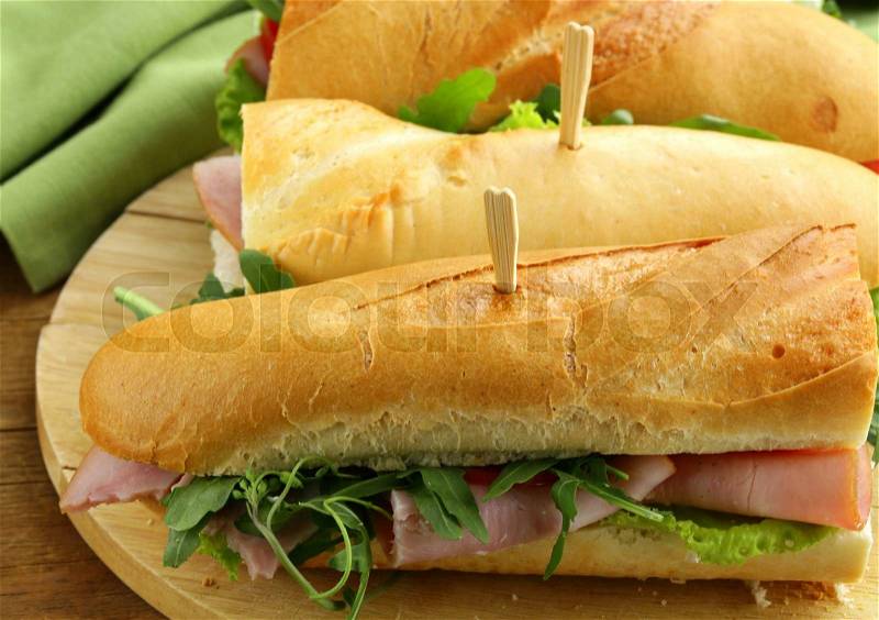 Baguette sandwich with arugula, ham and tomatoes, stock photo