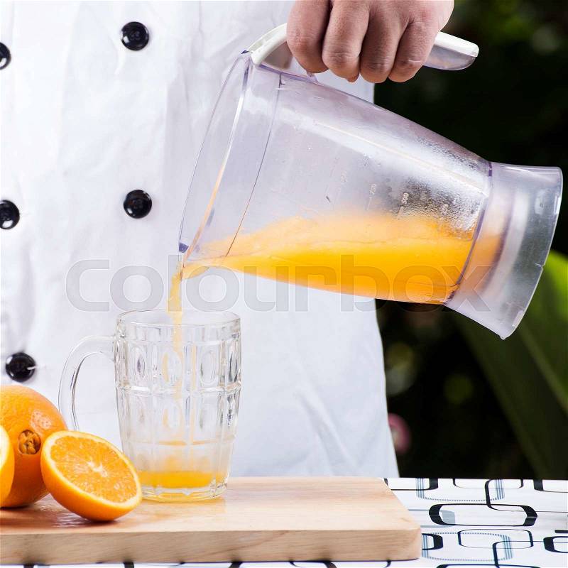Chef pouring orange juice smoothie to the glass, stock photo
