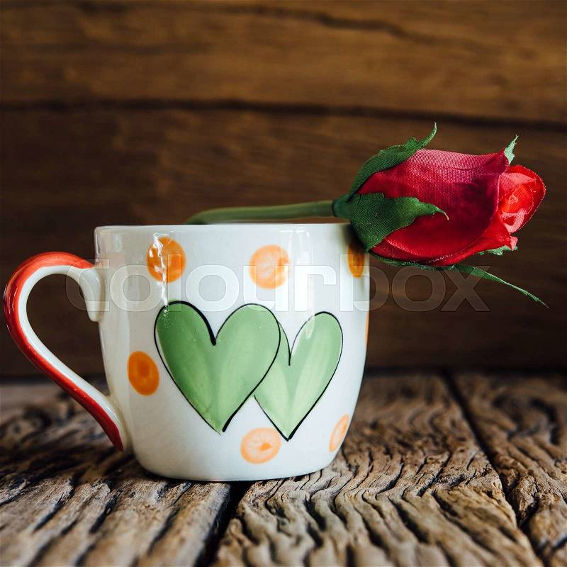 Vintage love cup with rose on old wood background, stock photo
