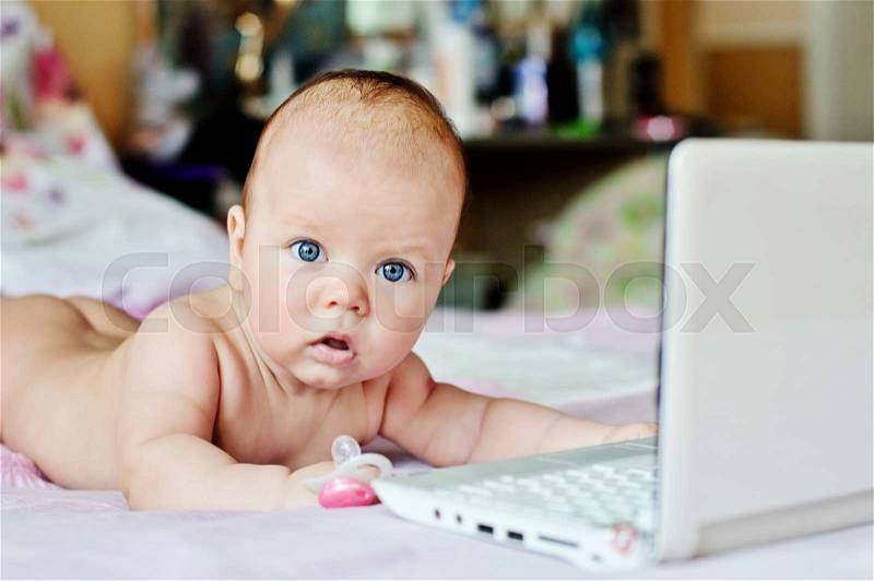 Three months baby with laptop at home, stock photo