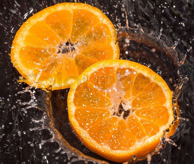 Orange in water splashes on a black background, stock photo