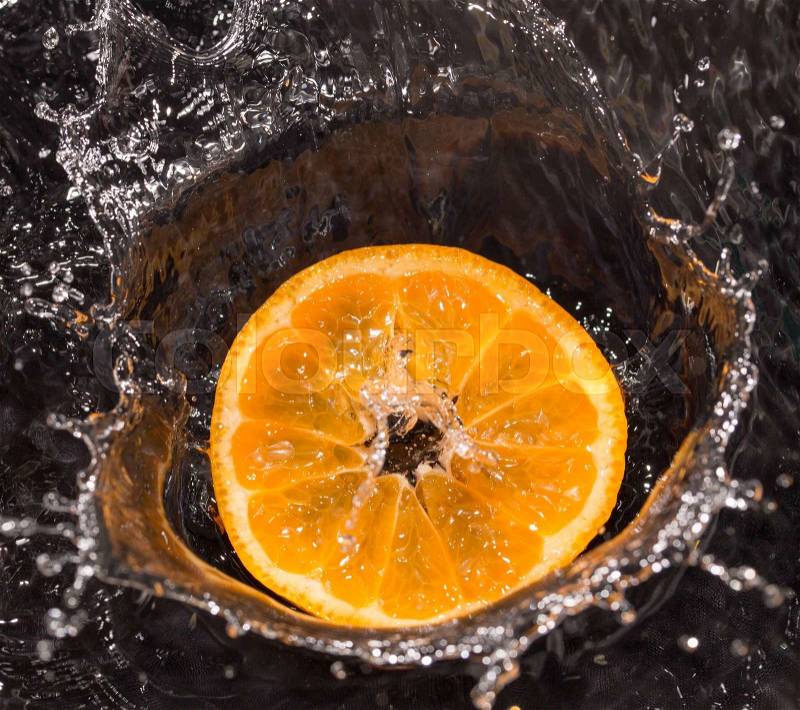 Orange in water splashes on a black background, stock photo