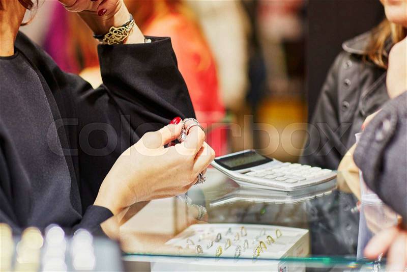 Jeweler helping client to choose a wedding ring, stock photo