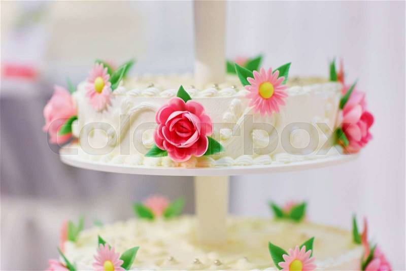 White wedding cake decorated with sugar flowers - pink roses and daisies, stock photo