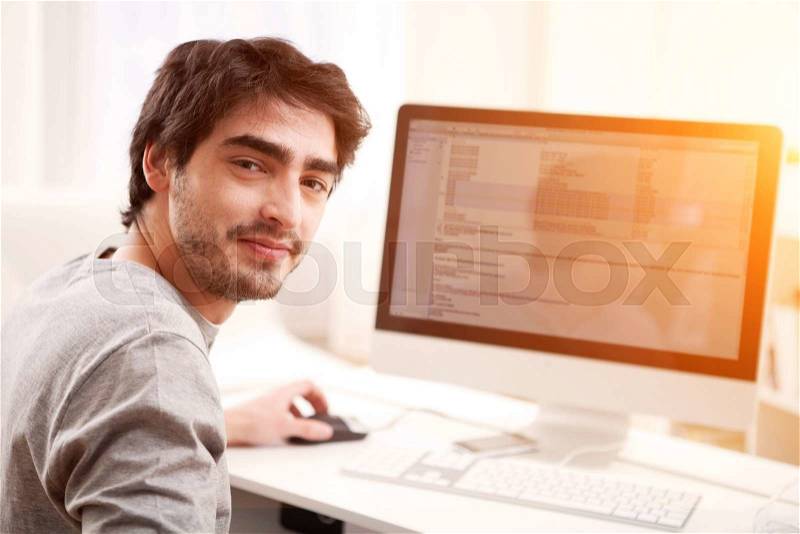 View of a Young smiling man in front of computer, stock photo