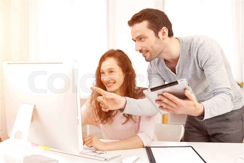 View of a Man working with his co-worker on computer, stock photo