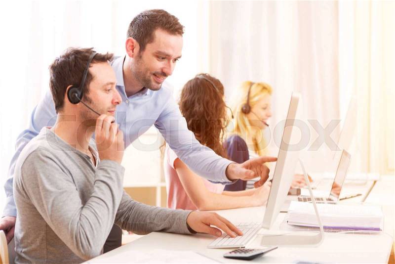 View of a Manager training a young attractive people on computer, stock photo