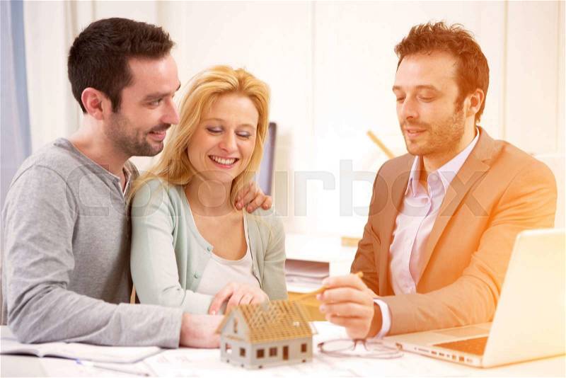 View of a Real estate agent present project on tablet to a young couple, stock photo