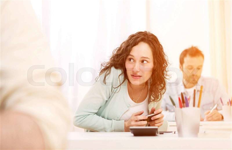 View of a Young attractive woman cheating with mobile during exam, stock photo