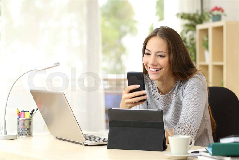 Happy woman working using multiple devices on a desk at home, stock photo