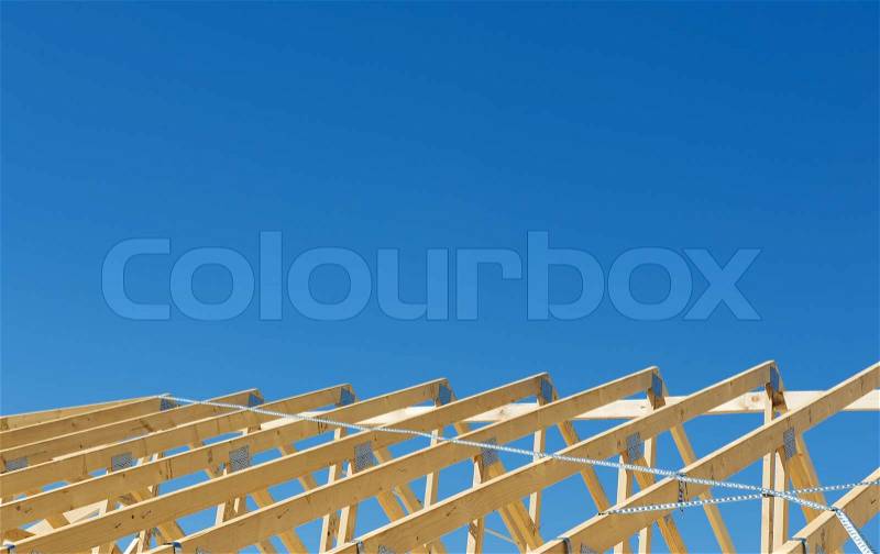 New residential construction home framing against a blue sky, stock photo