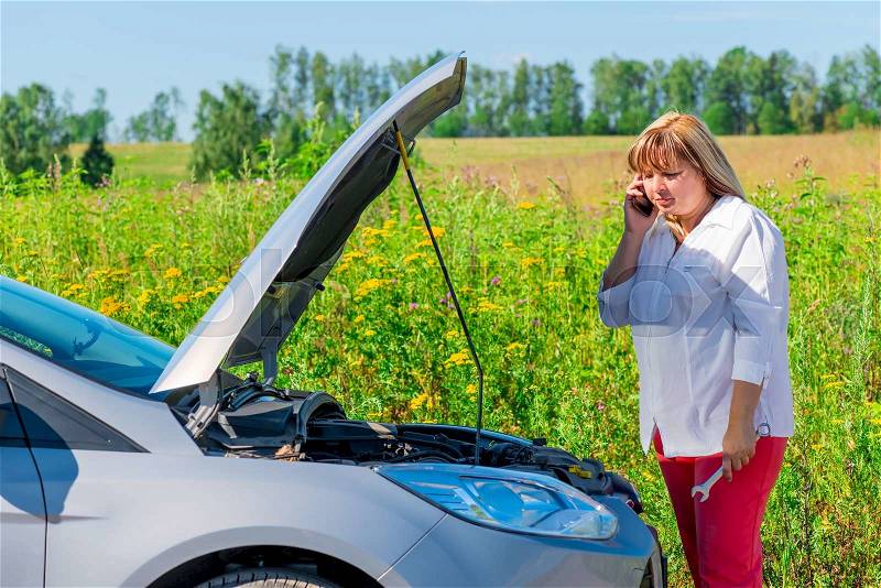 Woman looks at engine and speaks on the phone, stock photo