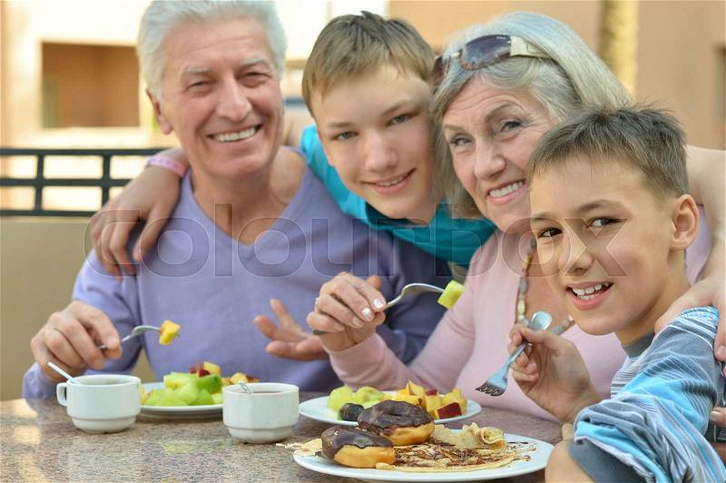 Grandparents with grandchildren at breakfast on tropical resort, stock photo