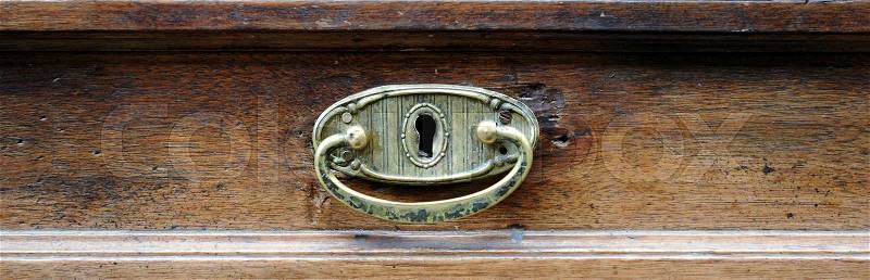 Brass handle of the drawer of an antique furniture, stock photo