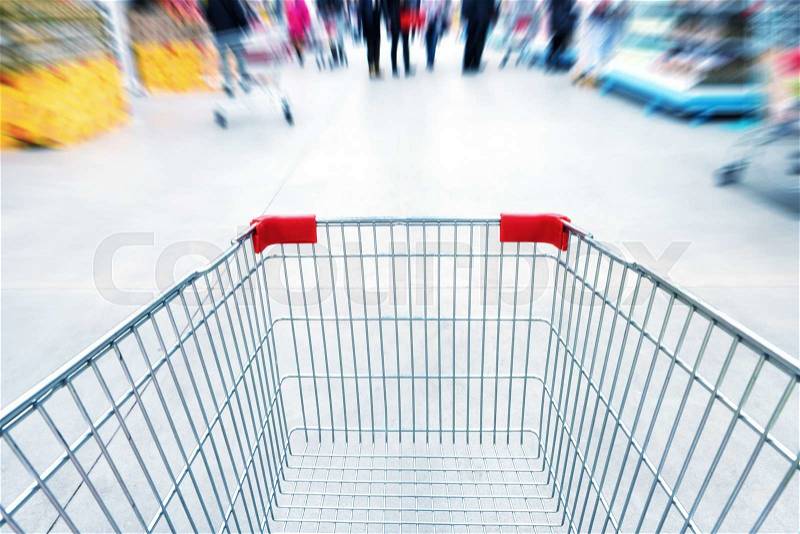 Empty trolley in supermarket or mall full of crowded people. Blur motion, stock photo
