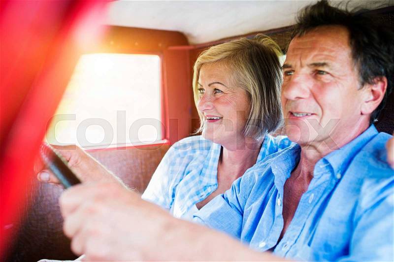 Senior couple in their vintage red car, stock photo