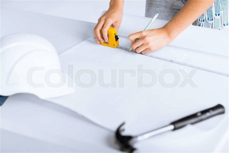 Architecture and home renovation concept - architect drawing on blueprint using flexible ruller, stock photo