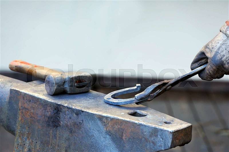 Blacksmith forges a horseshoe for horse, stock photo