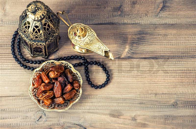 Ramadan lamp, rosary and dates on wooden background. Holidays decoration, stock photo