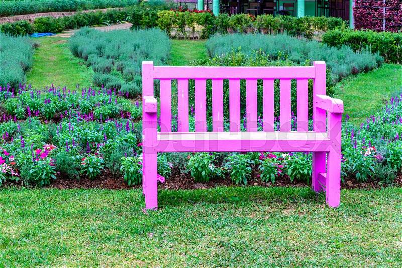 Pink wooden bench among the flower garden, stock photo