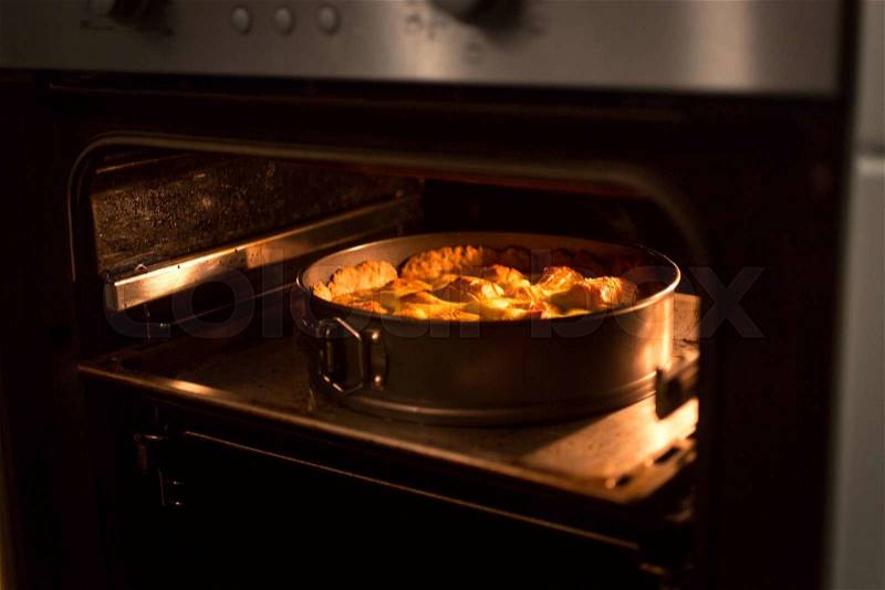 Closeup photo of apple pie baking in oven at kitchen, stock photo