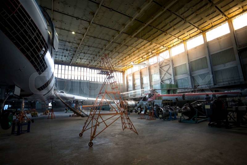 Sunset in big hangar with airplanes under heavy maintenance, stock photo