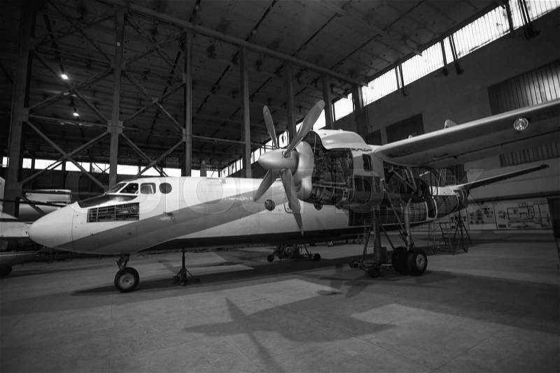 Black and white photo of cargo airplane in hangar under maintenance, stock photo
