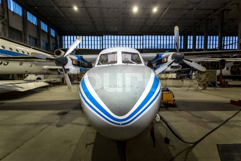 Front view of private airplane in hangar at night, stock photo