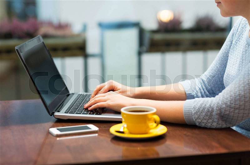 Business, people, technology and lifestyle concept - close up of woman typing on laptop with coffee and smartphone, stock photo