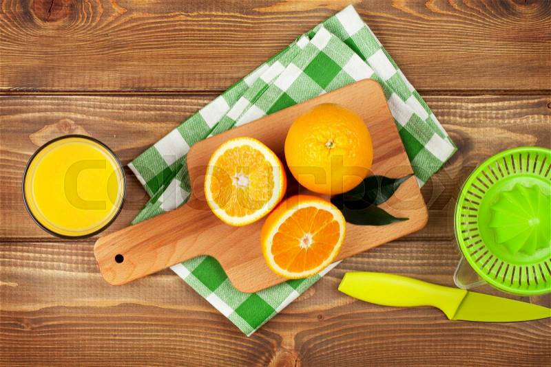 Orange fruits and glass of juice. Top view over wood table background, stock photo