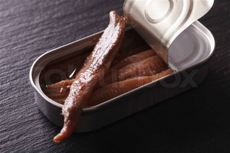 Anchovy fillets in tin macro on a slate board. Horizontal , stock photo
