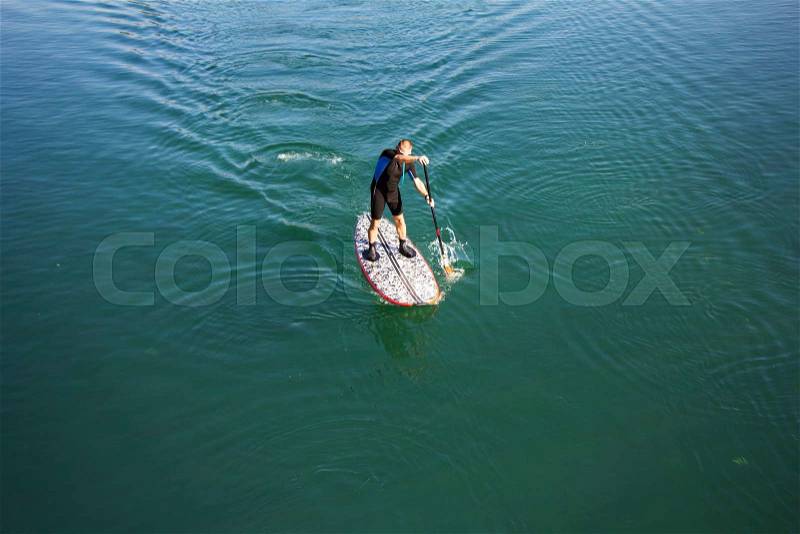 Stand up paddle board man paddleboarding on tranquil lake, stock photo