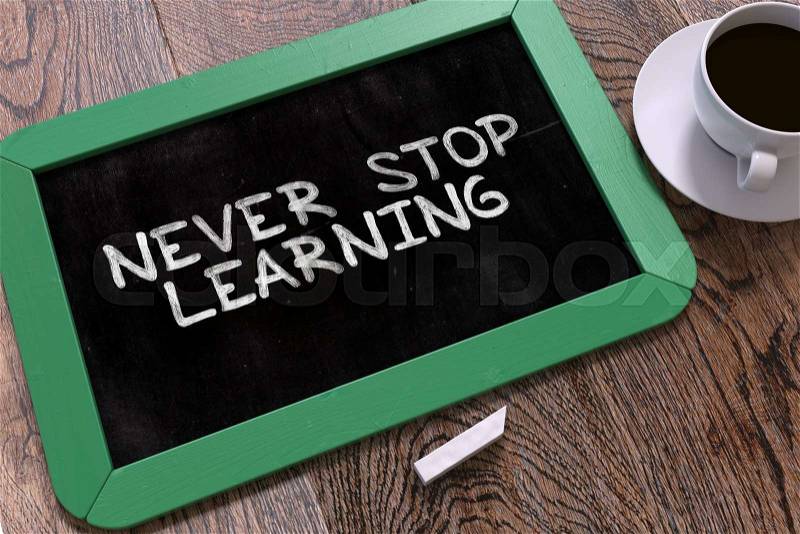 Never Stop Learning - Motivation Quote Handwritten on Green Chalkboard. Business Concept. Composition with Chalkboard and Cup of Coffee. Top View Image, stock photo