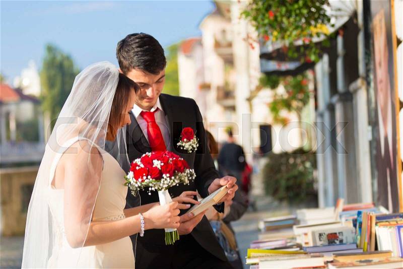 Bride and groom. Portrait of a loving wedding couple reviewing vintage books in antique book shop in medieval city center of Ljubljana, Slovenia, stock photo