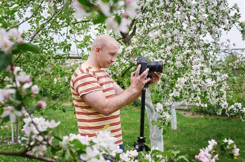 Man shoot at the camera in a blossoming spring garden, stock photo