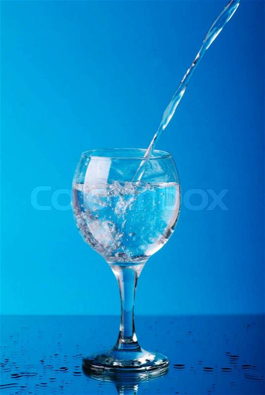 Pouring water into the glass on blue, stock photo