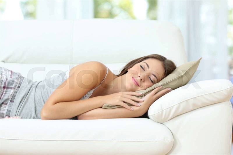 Beautiful girl sleeping or napping happy on a comfortable couch at home, stock photo